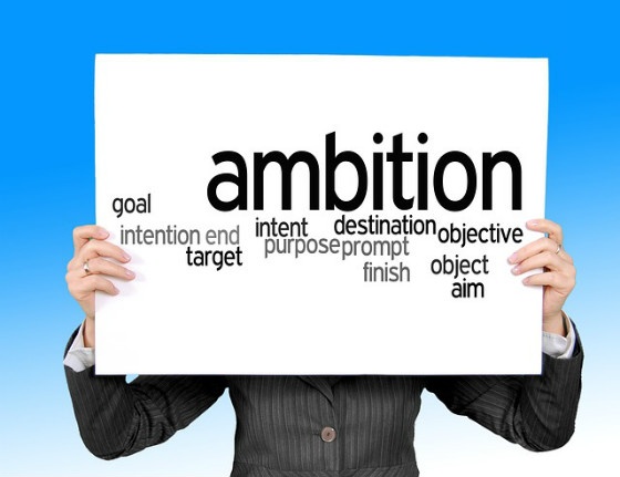 A person holding a sign that reads 'ambition', along with several synonyms.