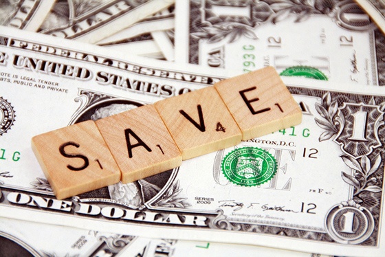 Money and Scrabble tiles spelling 'SAVE'.