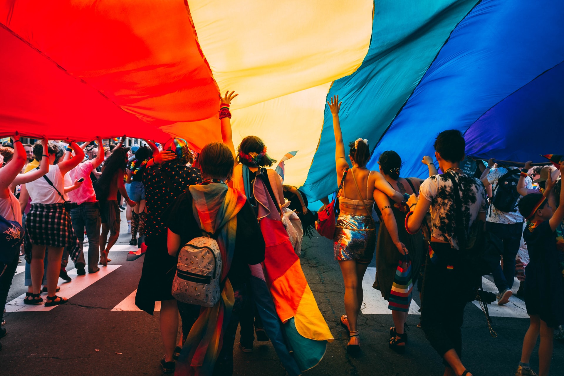 LGBTQ+ people beneath a pride flag